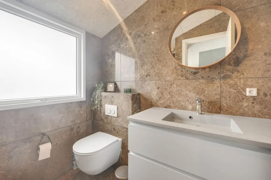Un baño con lavabo, inodoro y una ventana grande.