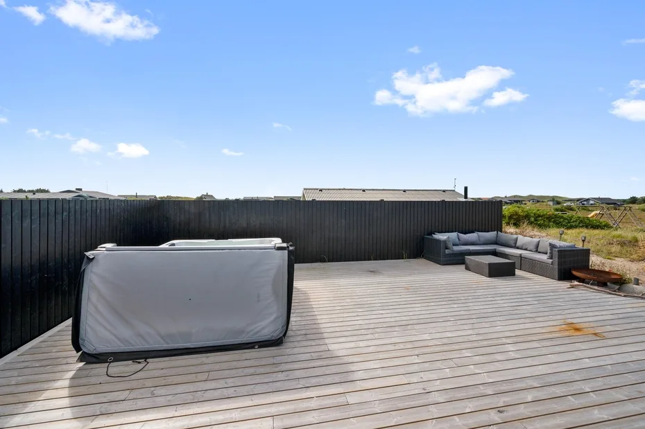 Una terraza en la azotea tiene una bañera de hidromasaje cubierta y asientos al aire libre.