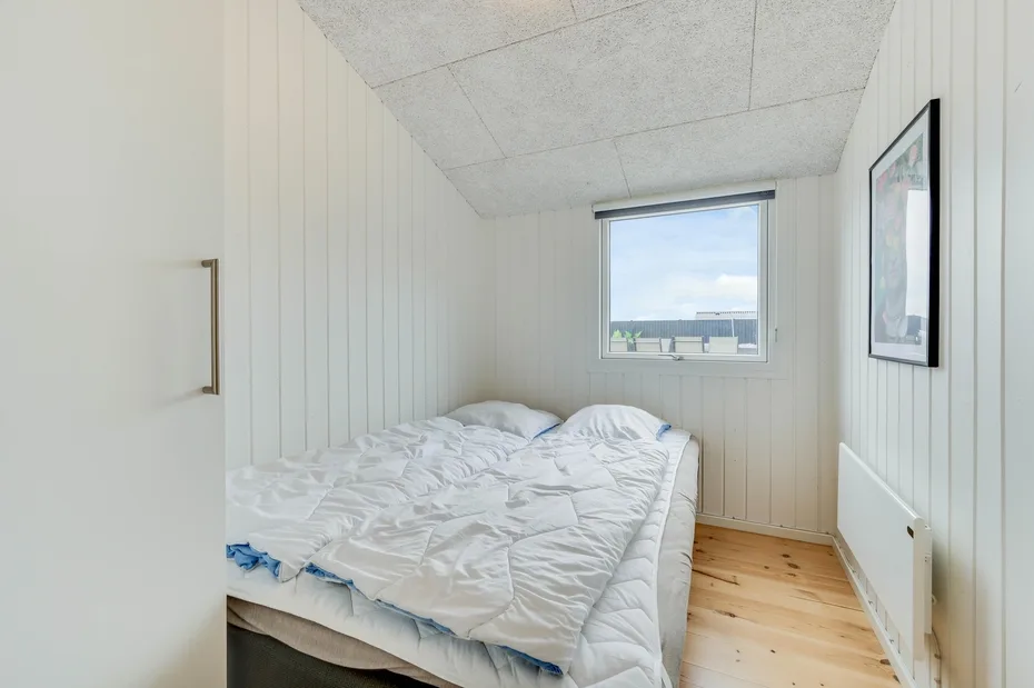 Un dormitorio luminoso con una cama bajo una ventana.