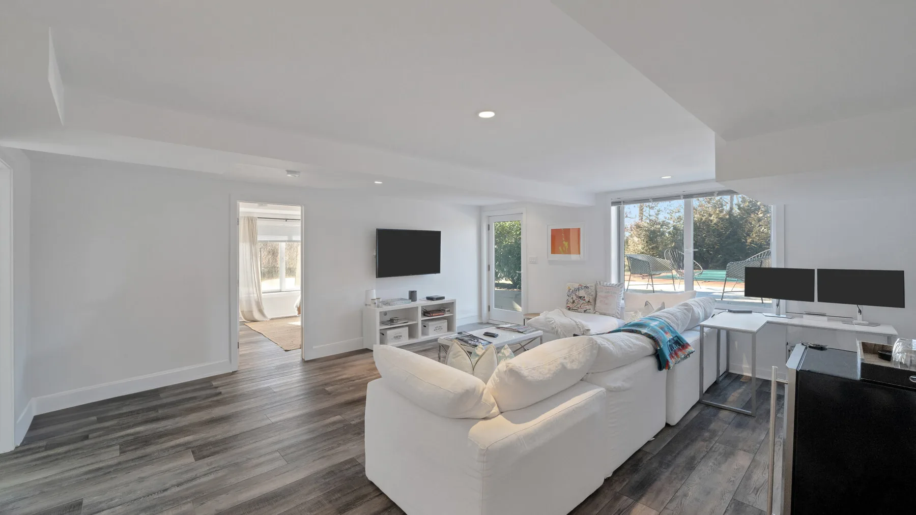 A bright living room with white seating and a large window.