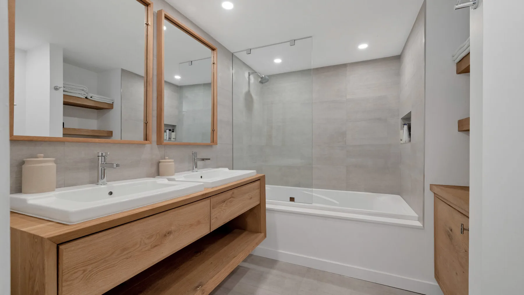 A modern bathroom with a double sink vanity and a bathtub.