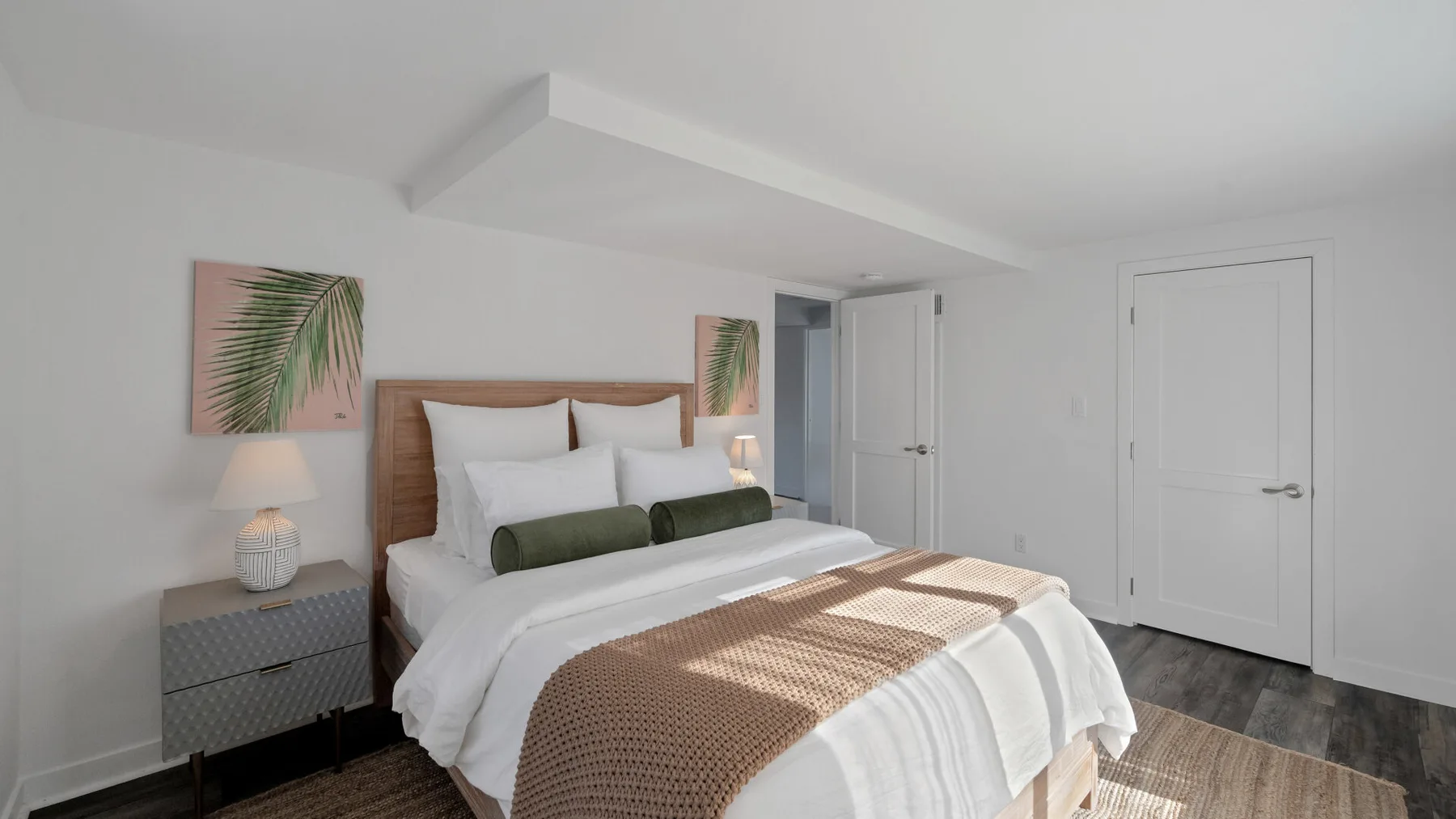 A bright bedroom with a neatly made bed and bedside tables.