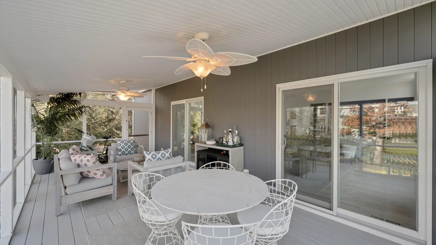 A covered patio with a round dining table and sliding glass doors.