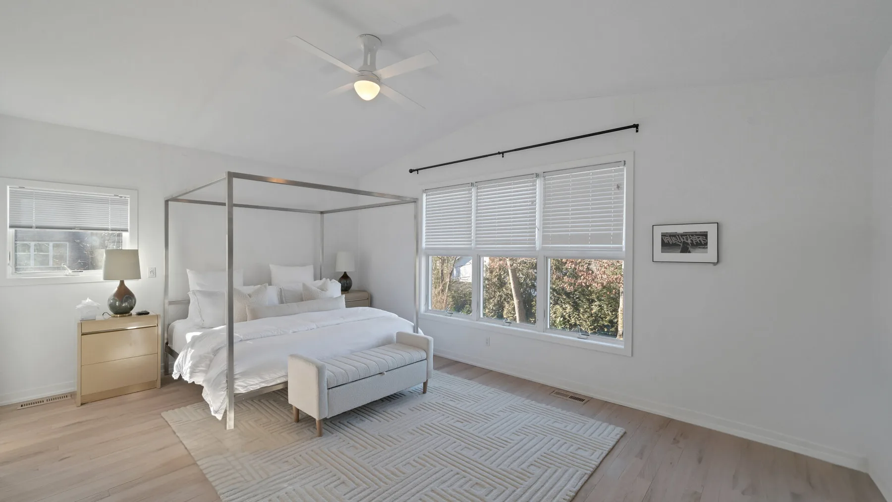 A bright bedroom with a canopy bed and large windows.