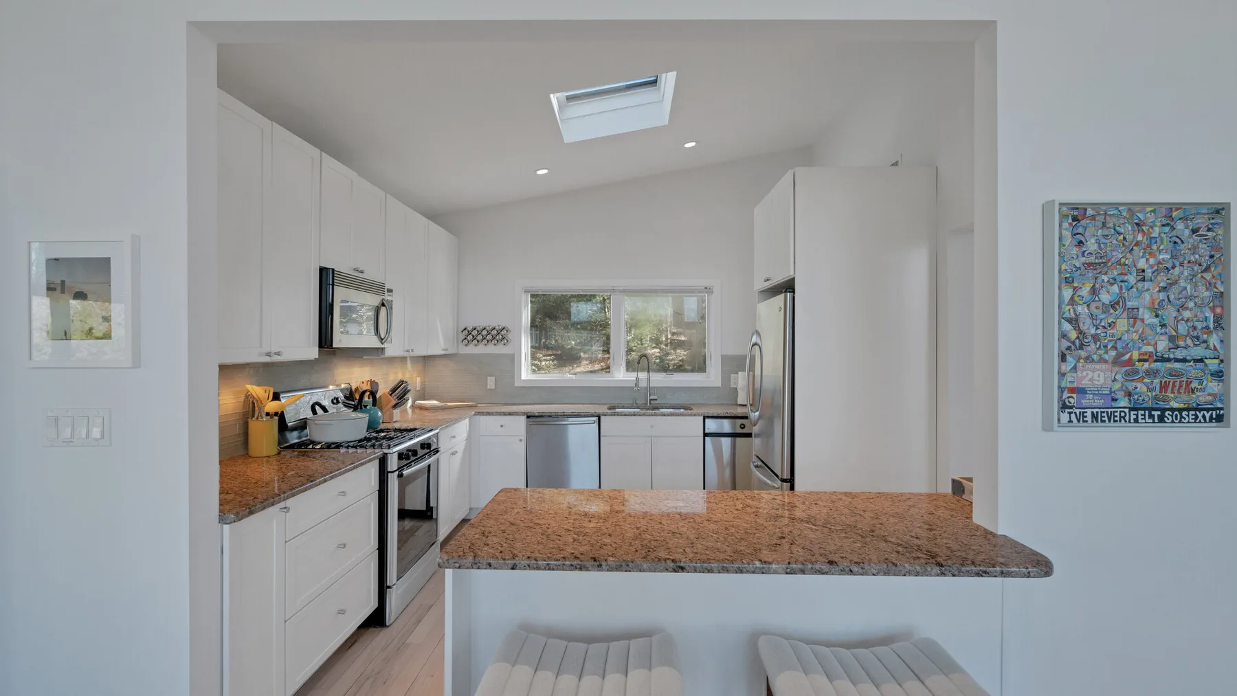 A bright kitchen with white cabinets and a stone-topped island.