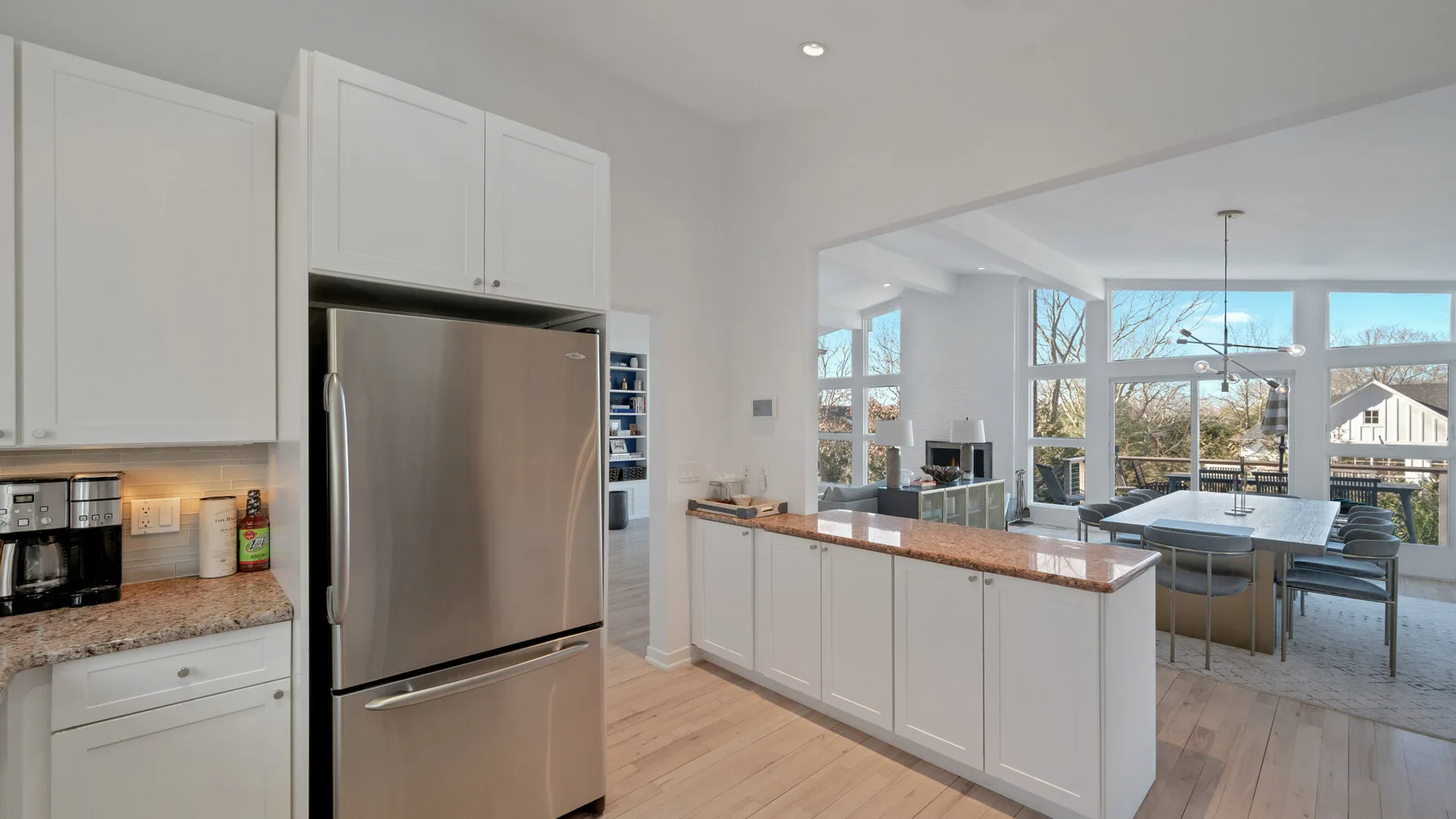 A bright kitchen with white cabinets and a counter opens onto a dining area.