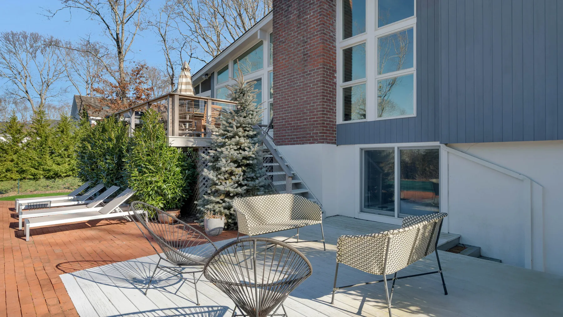 A brick-paved outdoor patio with lounge seating beside a modern house.