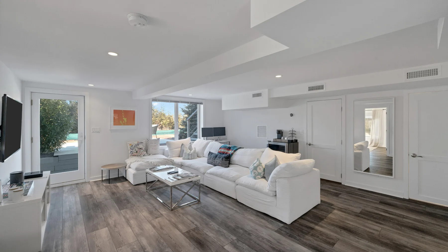 A bright living room with white seating arranged around a low coffee table.