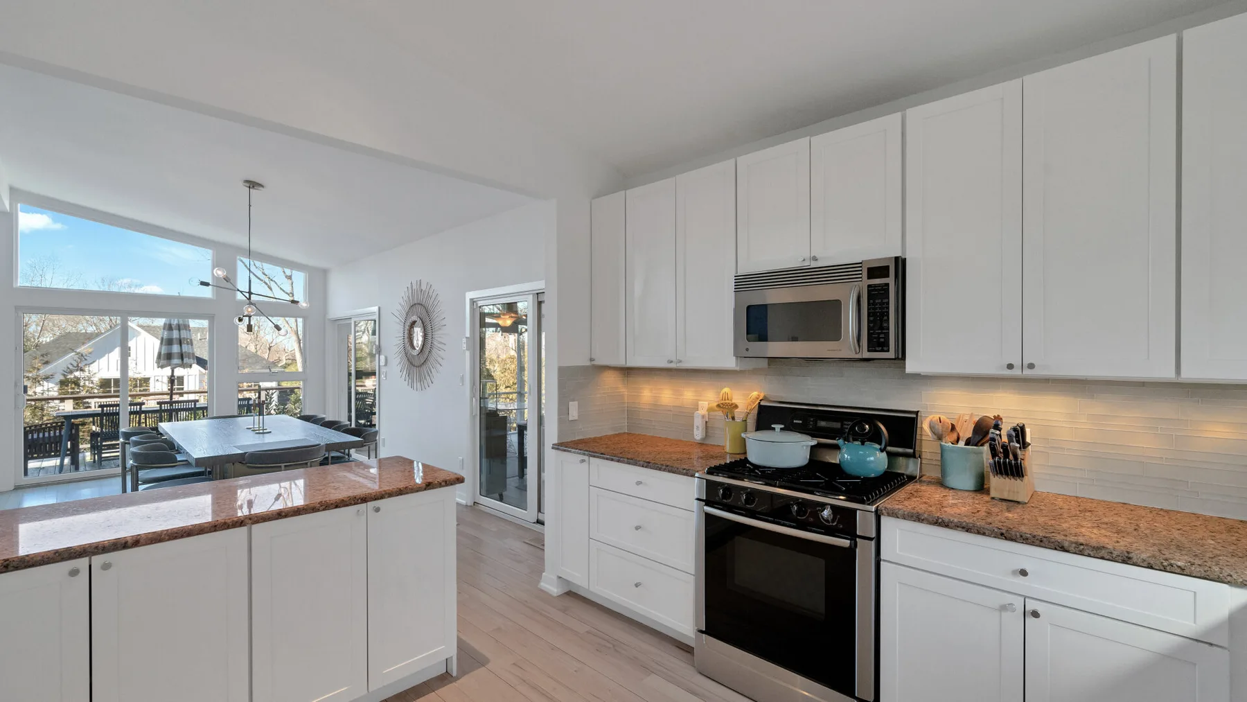 A bright kitchen with white cabinets, a central island, and large windows.