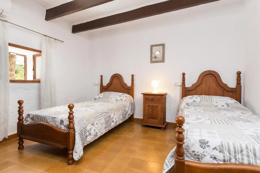 A bedroom with two wooden beds and a small bedside table between them.