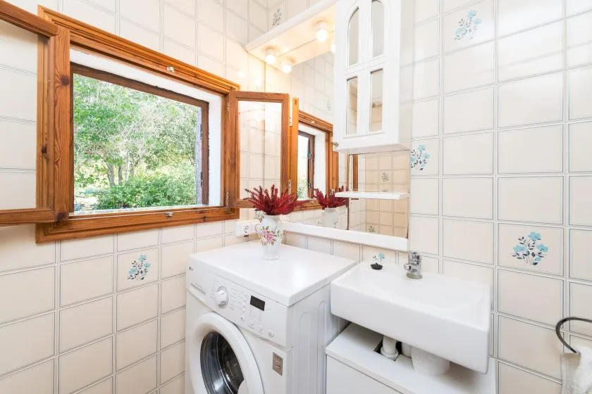 A tiled bathroom with a washing machine beside a white sink.