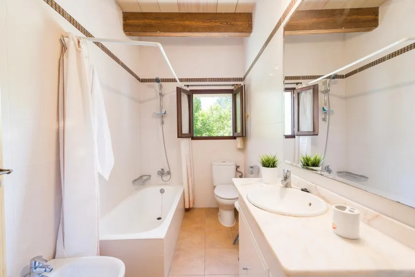 A bright bathroom with a bathtub, shower, and long sink counter.