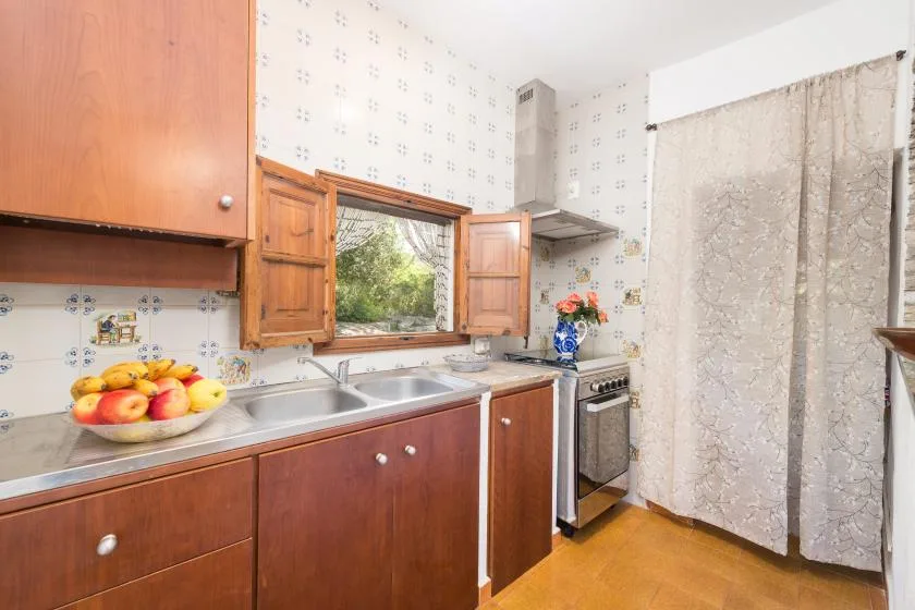 A kitchen with wooden cabinets, a sink, and a stove.