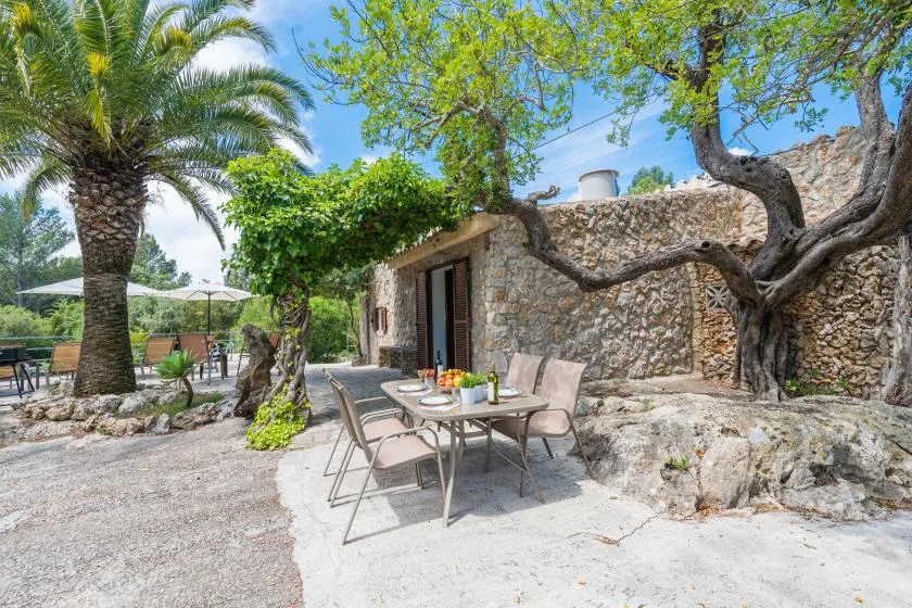 An outdoor dining area with a table and chairs beside a stone building.