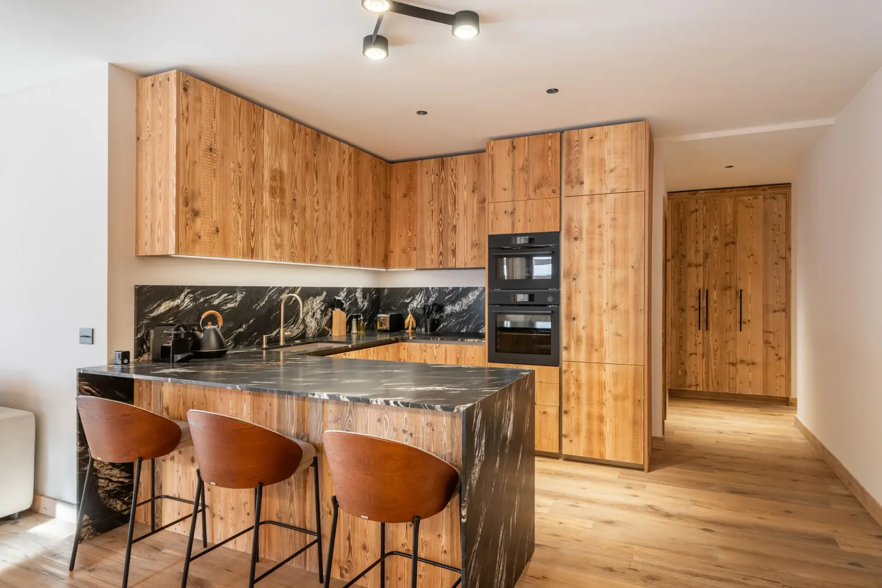 Una cocina con armarios de madera, encimeras oscuras y asientos de barra.