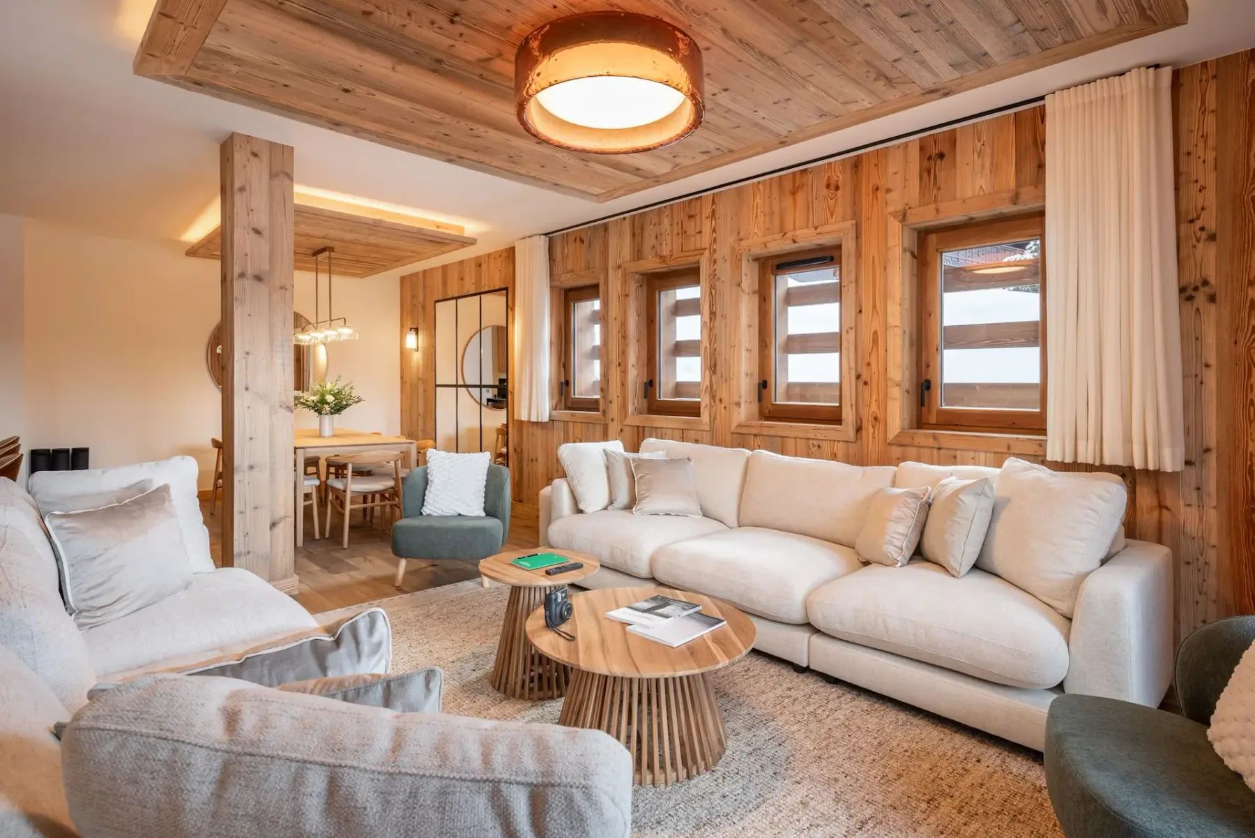 Una sala de estar revestida de madera con asientos claros y una mesa de centro redonda.