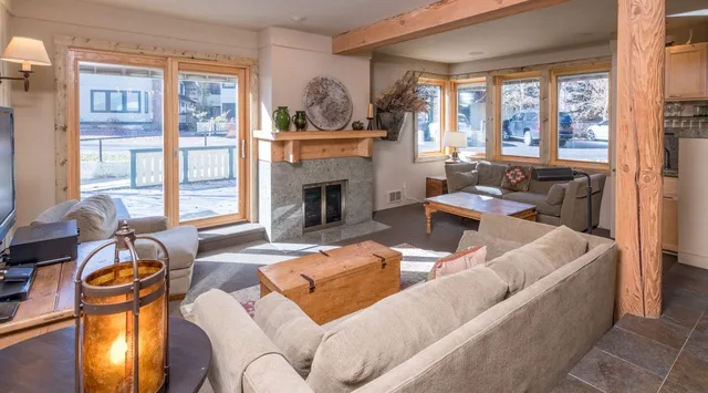 Una sala de estar con asientos alrededor de una chimenea y ventanas grandes.