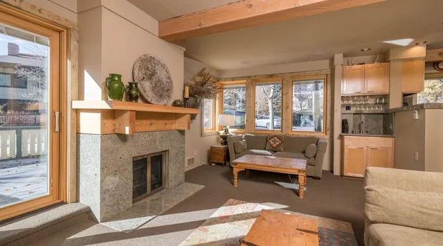 Una sala de estar con chimenea de piedra, asientos y una zona de cocina.