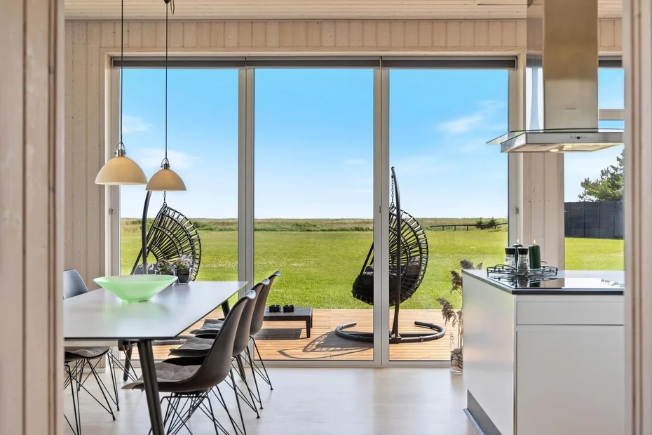 Una cocina y comedor de planta abierta dan a un patio con vistas a un campo verde.