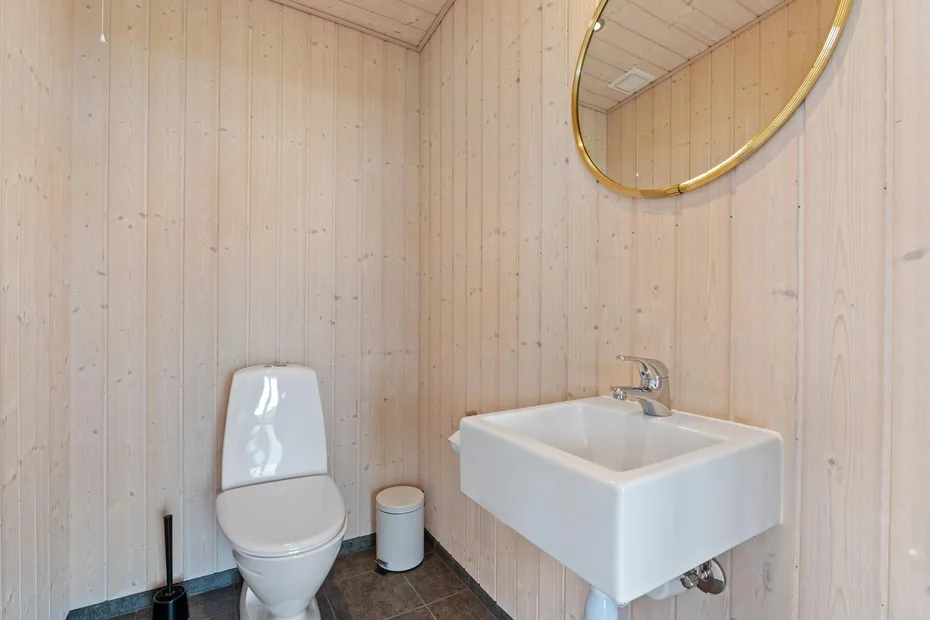 Un baño con lavabo de pared e inodoro.