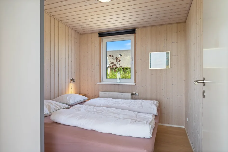 Un dormitorio con una cama doble junto a una ventana.