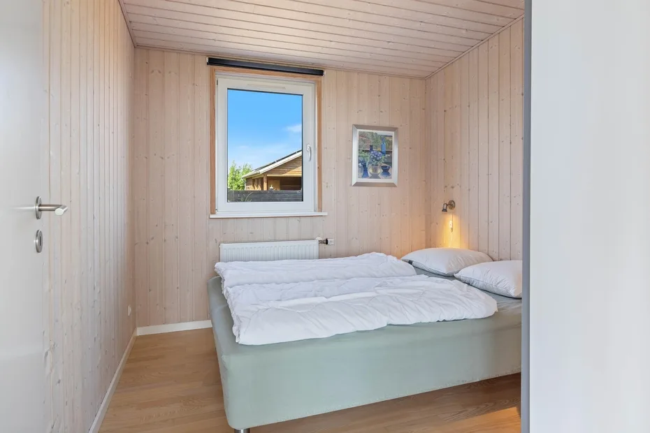 Un dormitorio con una cama debajo de una ventana.
