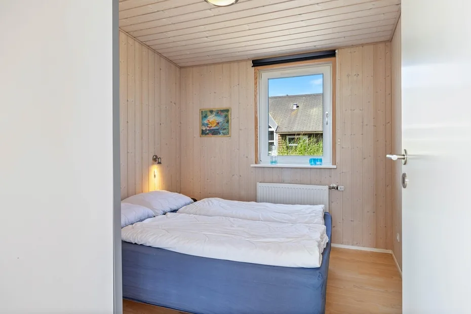 Un dormitorio pequeño con una cama debajo de una ventana.