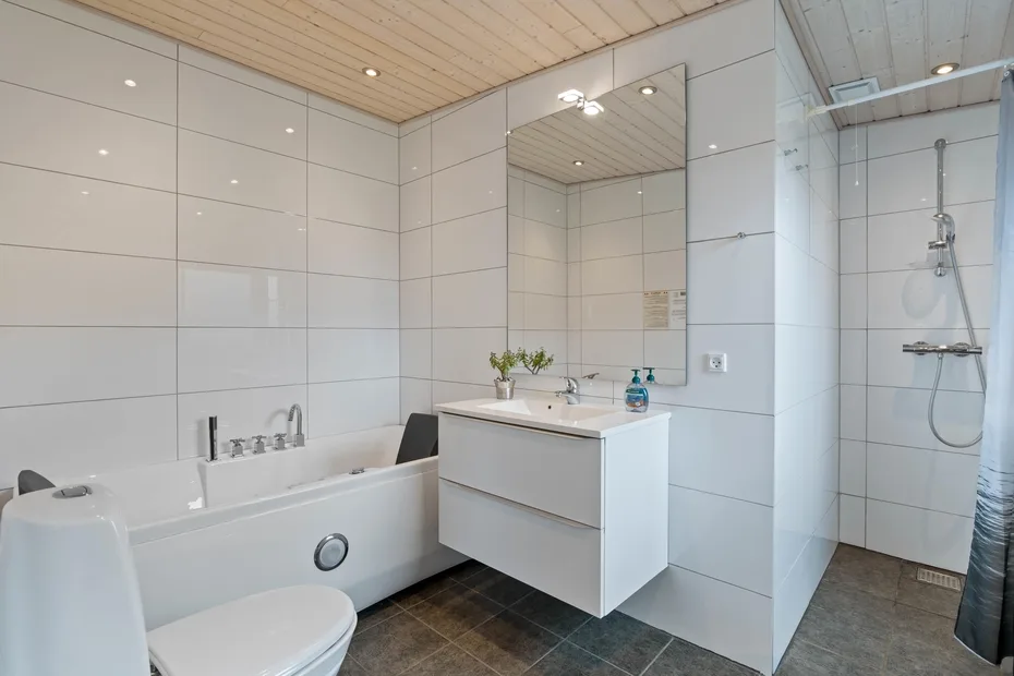 Un baño alicatado con bañera, lavabo y ducha.