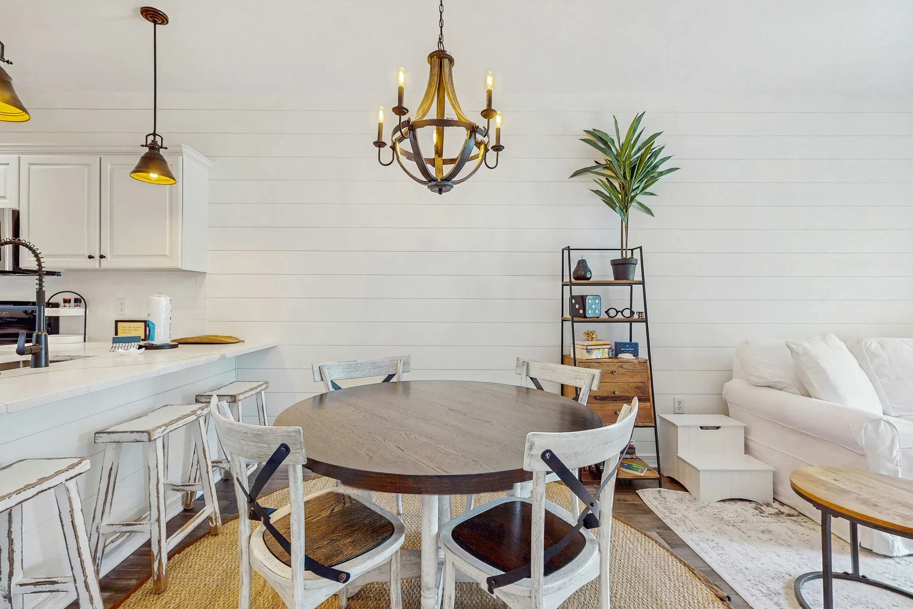 A dining area with a round table and white seating beside an open kitchen.