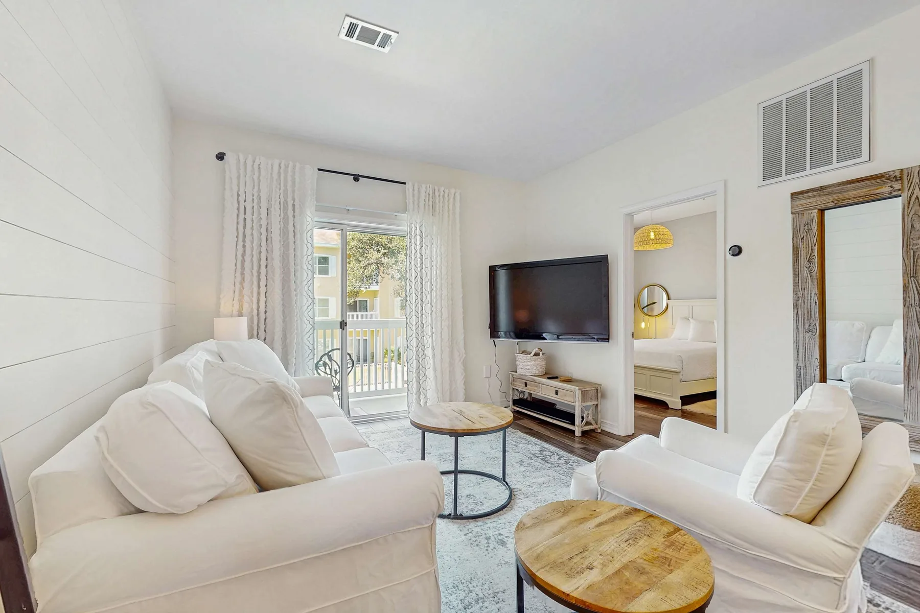 A bright living room with seating, a television, and a round coffee table.