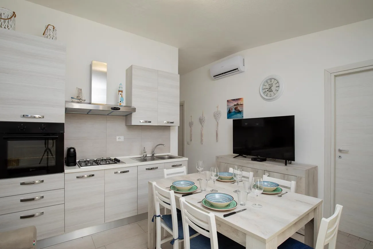 Una cocina y comedor luminosos con una mesa puesta junto al televisor.