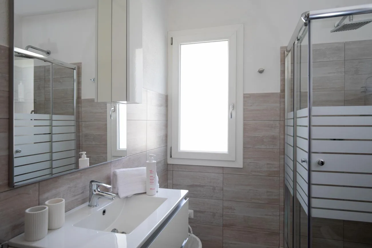 Un baño con lavabo, espejo y ducha de vidrio.