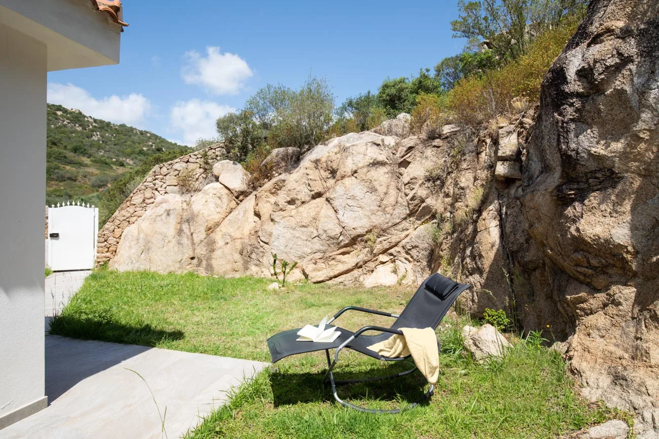 Un patio exterior tiene una tumbona reclinable junto a una ladera rocosa.
