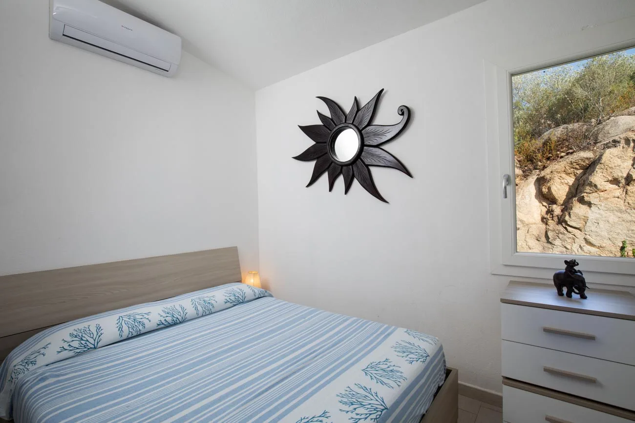 Un dormitorio con una cama y una ventana con vista a un terreno rocoso.