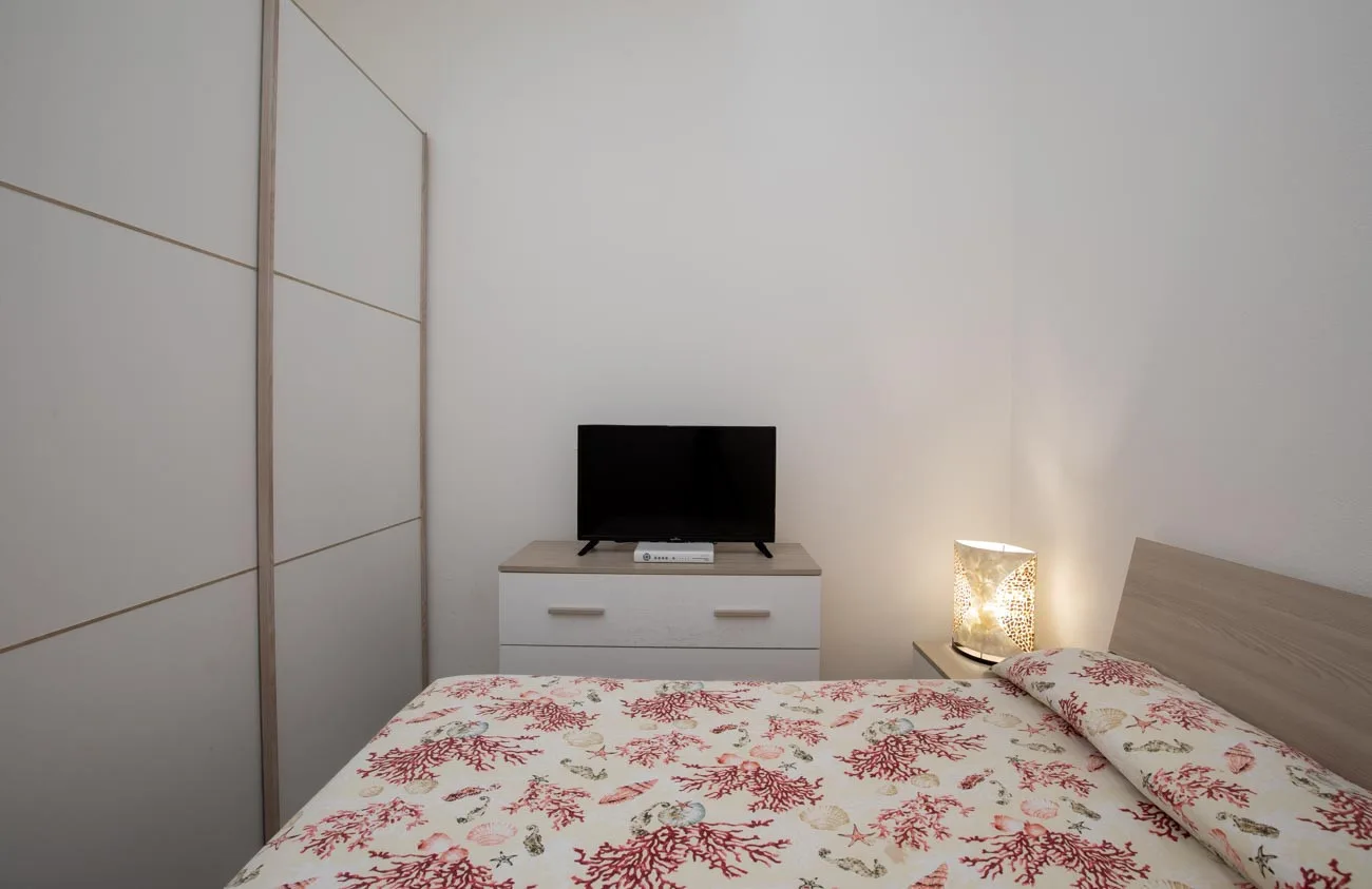 Un dormitorio con una colcha floral, una cómoda y un televisor.