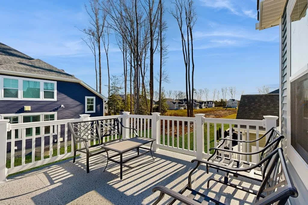 An outdoor deck with seating overlooks neighboring houses and leafless trees.