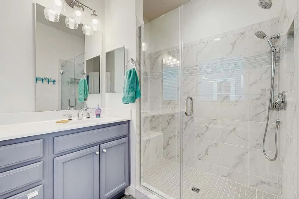 Un baño luminoso con tocador y ducha con mampara de vidrio.