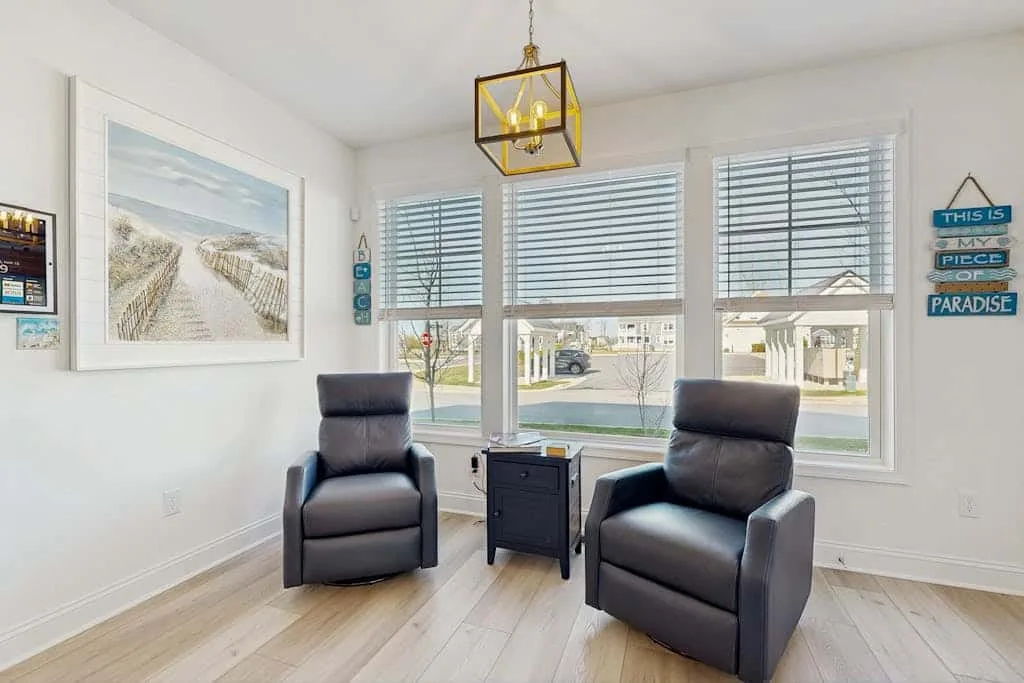 Una luminosa sala de estar con dos sillones frente a grandes ventanas.