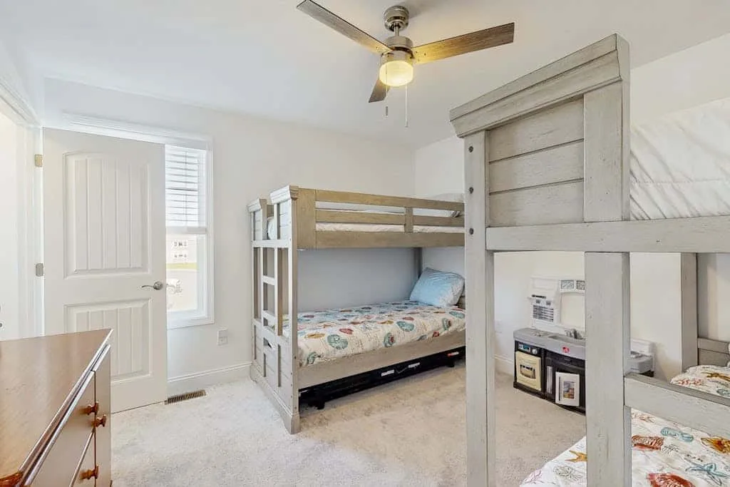 Un dormitorio luminoso con literas de madera y ropa de cama estampada.