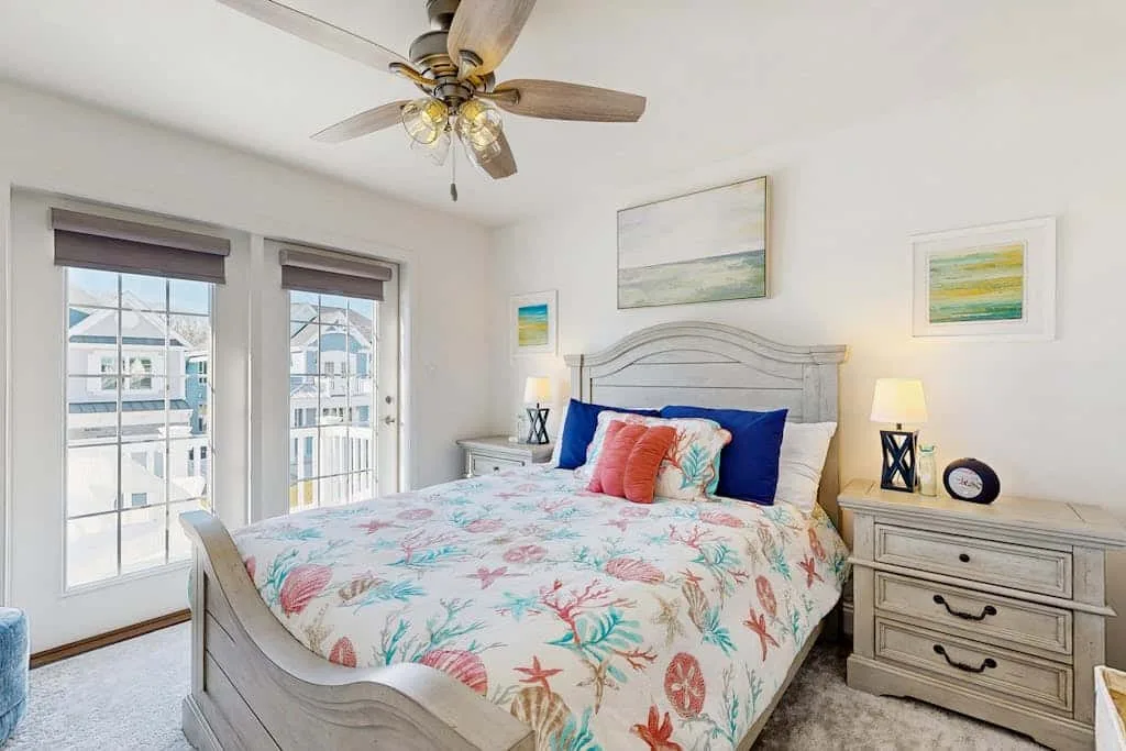 Un dormitorio luminoso con una cama cubierta con ropa de cama floral colorida.