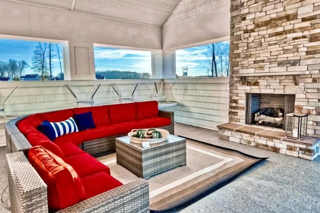 Una sala luminosa con asientos rojos, una mesa baja y una chimenea de piedra.