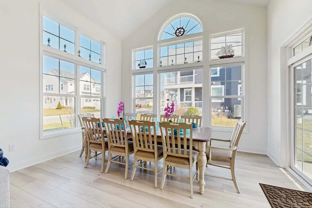 A bright dining area with a wooden table and large windows.