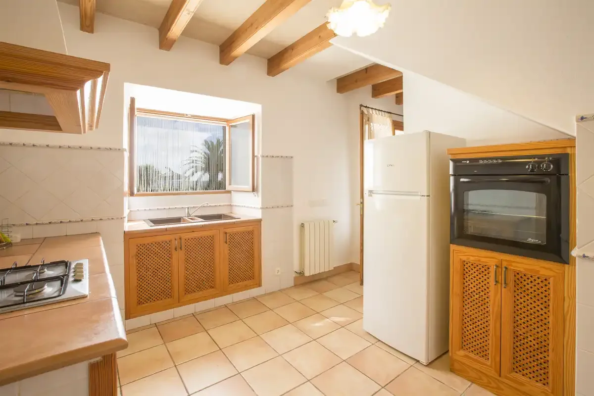 A bright kitchen with a refrigerator, oven, and tiled floor.