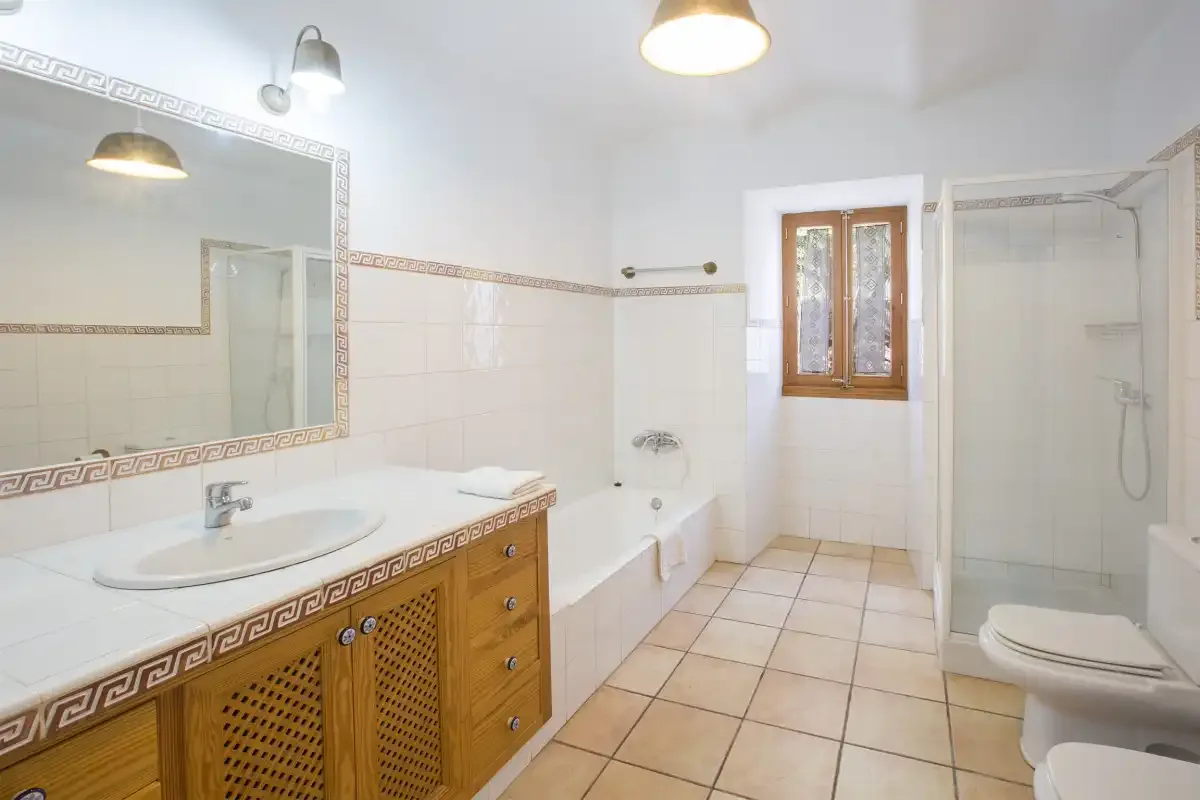 A tiled bathroom with a sink, bathtub, shower, and toilet.