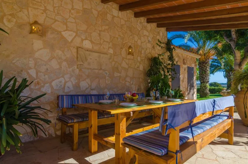 A covered outdoor dining area with a long wooden table and built-in seating.