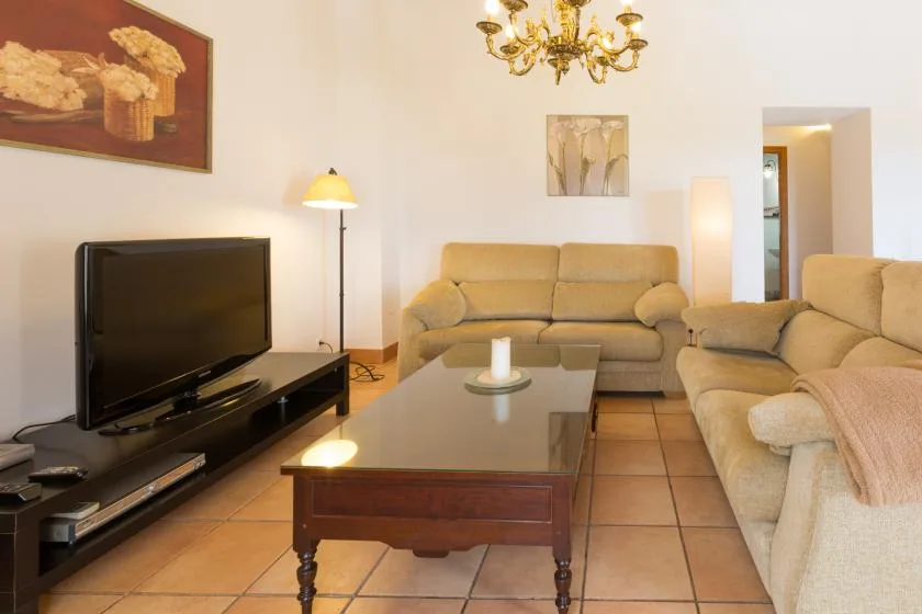 A living room with beige seating, a television, and a coffee table.