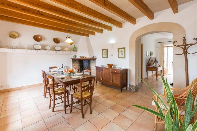 A dining room with a wooden table and chairs beneath exposed ceiling beams.