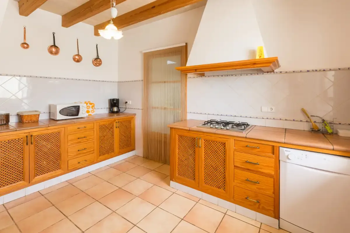 A spacious kitchen with wooden cabinetry, tiled flooring, and a central cooking area.