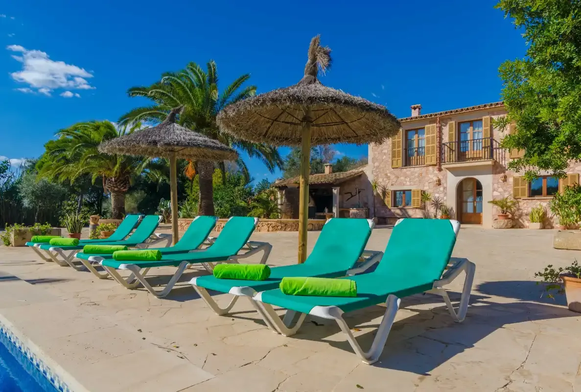 A sunny poolside terrace with turquoise loungers and thatched parasols.