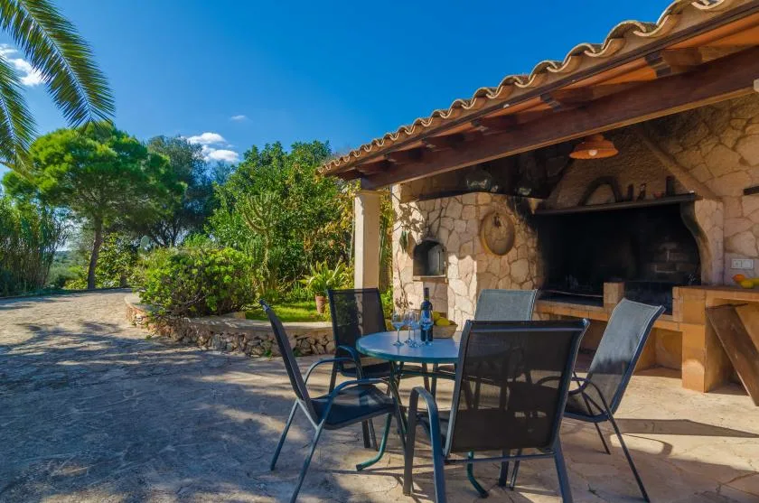 An outdoor patio with a dining table beside a stone fireplace.